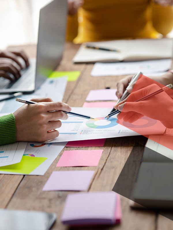 Hands reviewing printed marketing charts and notes on a table